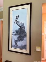 Full view of framed pelican print hung on wall