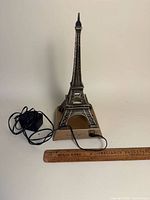 Front view of Eiffel Tower model with power adapter and ruler for scale