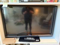 Front view of Toshiba flat screen TV on stand with remote in front