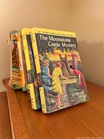 Front view of Nancy Drew #40 with additional yellow Nancy Drew volumes and other books behind