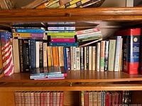 Shelf with approximately 40 assorted books, mix of hardcovers and paperbacks