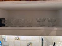Shelf view showing all twelve crystal coupe glasses arranged in two rows