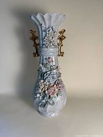 Front view of tall porcelain vase with applied flowers and gold handles