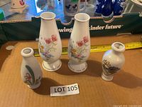 Four porcelain floral bud vases arranged together showing sizes and designs