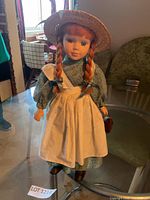 Full view of Anne of Green Gables doll standing on glass table