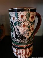 Full view of ceramic pitcher showing floral and bird design