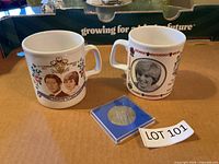 Overall lot showing two commemorative mugs and Westminster Abbey medallion in case