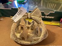 Front view of carved winter village figurine showing bow and buildings