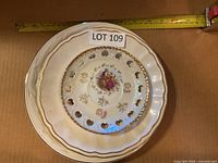 Stack of plates showing top reticulated heart-cutout porcelain plate and additional plates beneath with tape for scale
