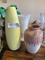 front view of yellow ceramic vase, white milk glass vase behind, drip glaze vase and part of clear glass vase