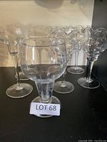 Group view of assorted clear glass stemmed candlesticks on shelf