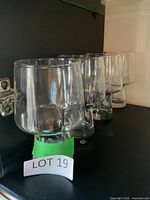 four clear pedestal glasses lined on shelf