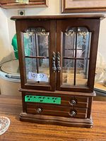 Front view of wood jewelry cabinet with size note attached