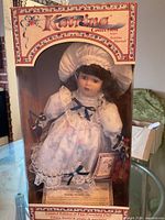 Front view of boxed porcelain doll showing full packaging and contents
