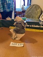 Side view showing adult bear wearing sweater and scarf holding cub with measuring tape indicating height