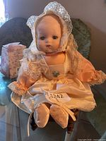 Front view of porcelain baby doll seated on wooden chair