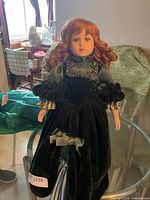 Full view of porcelain doll on stand showing dress and overall height