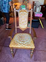Full view of one armchair showing wood frame, carved crest, upholstered back and seat