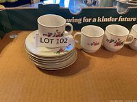Stacked saucers beside three cups showing pattern and gold rim