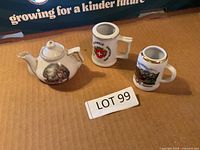 Three miniature porcelain Swiss souvenir pieces on cardboard background