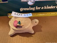 Top view of sand-textured turtle trinket box with lid on, measuring tape for scale