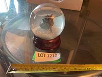 Full view of snow globe on base with measuring tape for scale