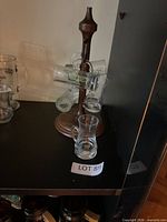 Overall view of stand on shelf with glasses attached and one additional glass in front