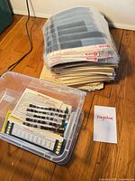 Stack of archival sleeve pages, stack of envelopes, plastic tub with envelopes and negatives, note card marked 'Negatives'