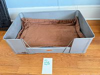 Full view of gray metal dog bed with brown cushion