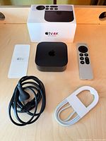 All components laid out: Apple TV box, remote, power cord, USB-C cable, original box and paperwork