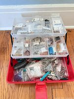 Three-tier tackle box open showing numerous bags of jump rings and tools