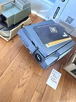 Grey Bell & Howell Monitor 960 projector with manuals stacked on top