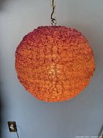 Full view of spherical orange and pink pendant light hanging from chain