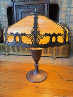 Full view of lamp illuminated showing shade color, base design, and power cord