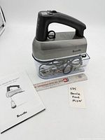 mixer seated on storage case with accessories inside and manual beside