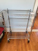 Front view showing three wire shelves, chrome frame, casters