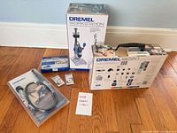 All boxed Dremel items arranged on floor: rotary tool kit, workstation, flex shaft, accessory kit, two EZ Lock wheels