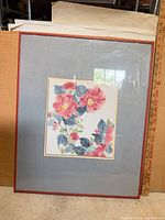 Full view of framed floral watercolor print with red frame and gray mat