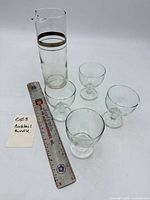 Full set showing one pitcher and four glasses next to ruler for scale