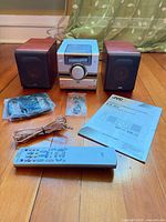 Full set showing main unit, two speakers, remote, manual, cables, antennas