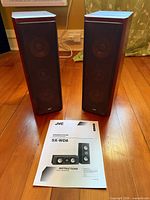 Pair of speakers standing with manual on floor