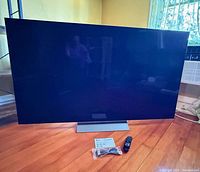Front view of LG 65-inch OLED TV on stand with accessories laid out