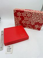 Red gift box and patterned sleeve side by side with ruler for scale