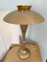 Full view of gold metal saucer lamp showing shade, stem and base