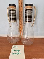 Both Pyrex carafes standing beside ruler showing height