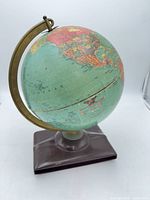 Full view of globe on base showing overall form, meridian and map colors