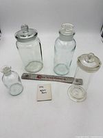 Group shot of four KIMAX glass apothecary jars with ruler for scale