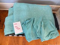 Folded turquoise woven tablecloth and stack of napkins