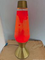 Full view of brass-tone lava lamp illuminated