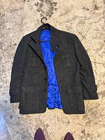 Full view front of charcoal grey jacket showing pockets and blue lining